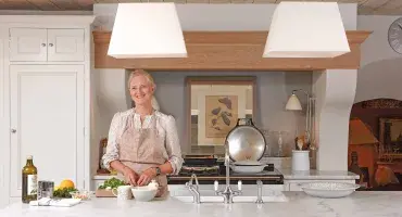 Emma Sims Hilditch in her kitchen standing in front of a White AGA eR7 100 cooker
