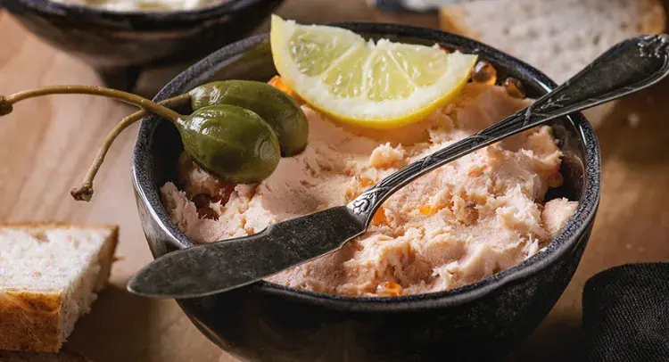 Salmon pate in a bowl with a lemon 